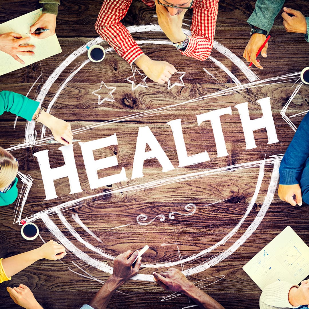 Gruppe von Fachkräften aus dem Gesundheitswesen bei der interdisziplinären Planung mit dem Wort HEALTH im Zentrum